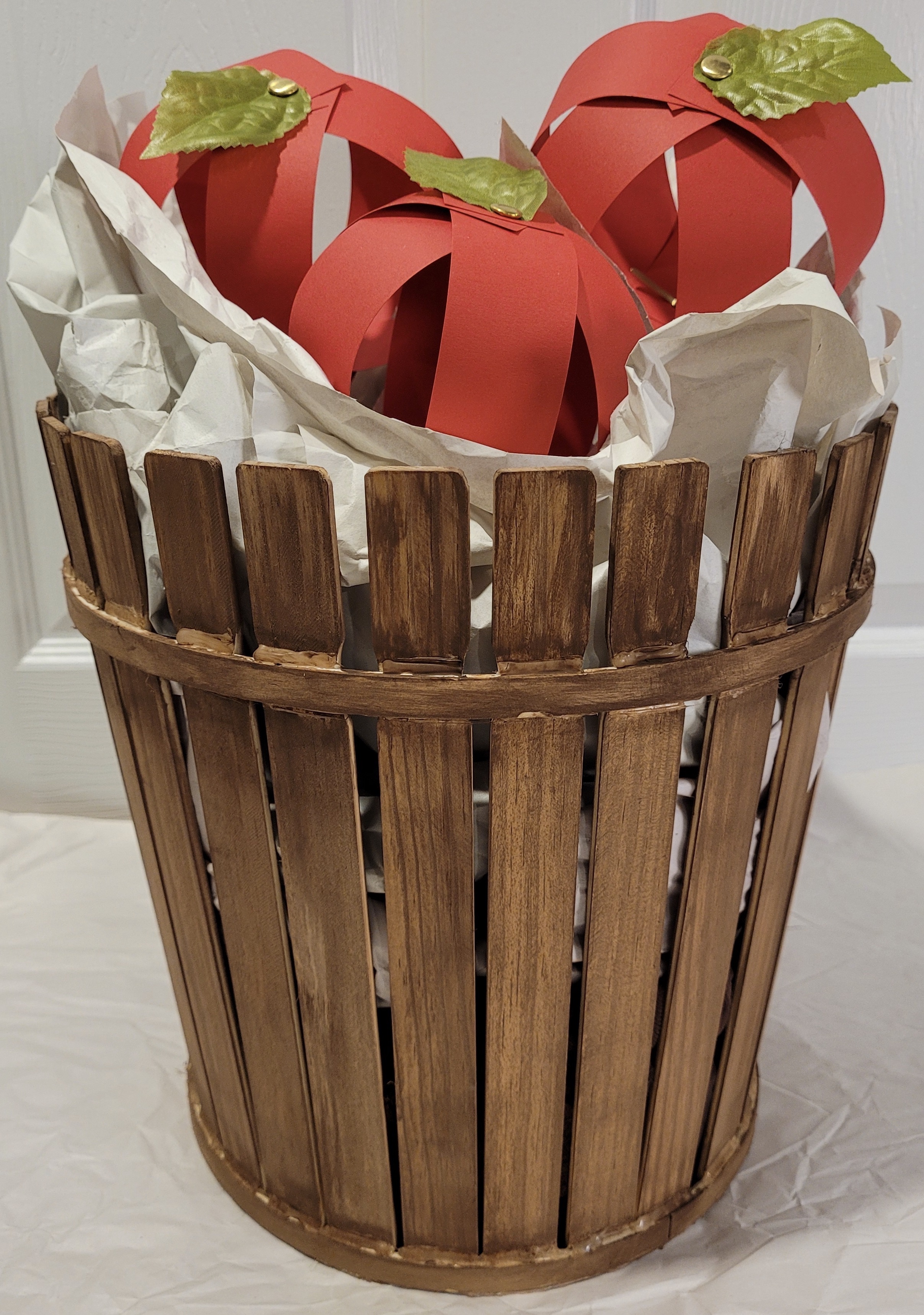red paper apples in tall brown wood slat basket