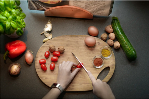 Image of hands slicing grape tomatoes on a cutting board.