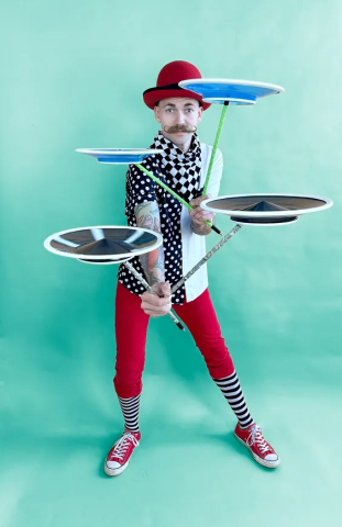 A man juggling 4 plates on long sticks. 