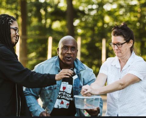 Terrence in the middle of two adult volunteers preparing for a magic trick.